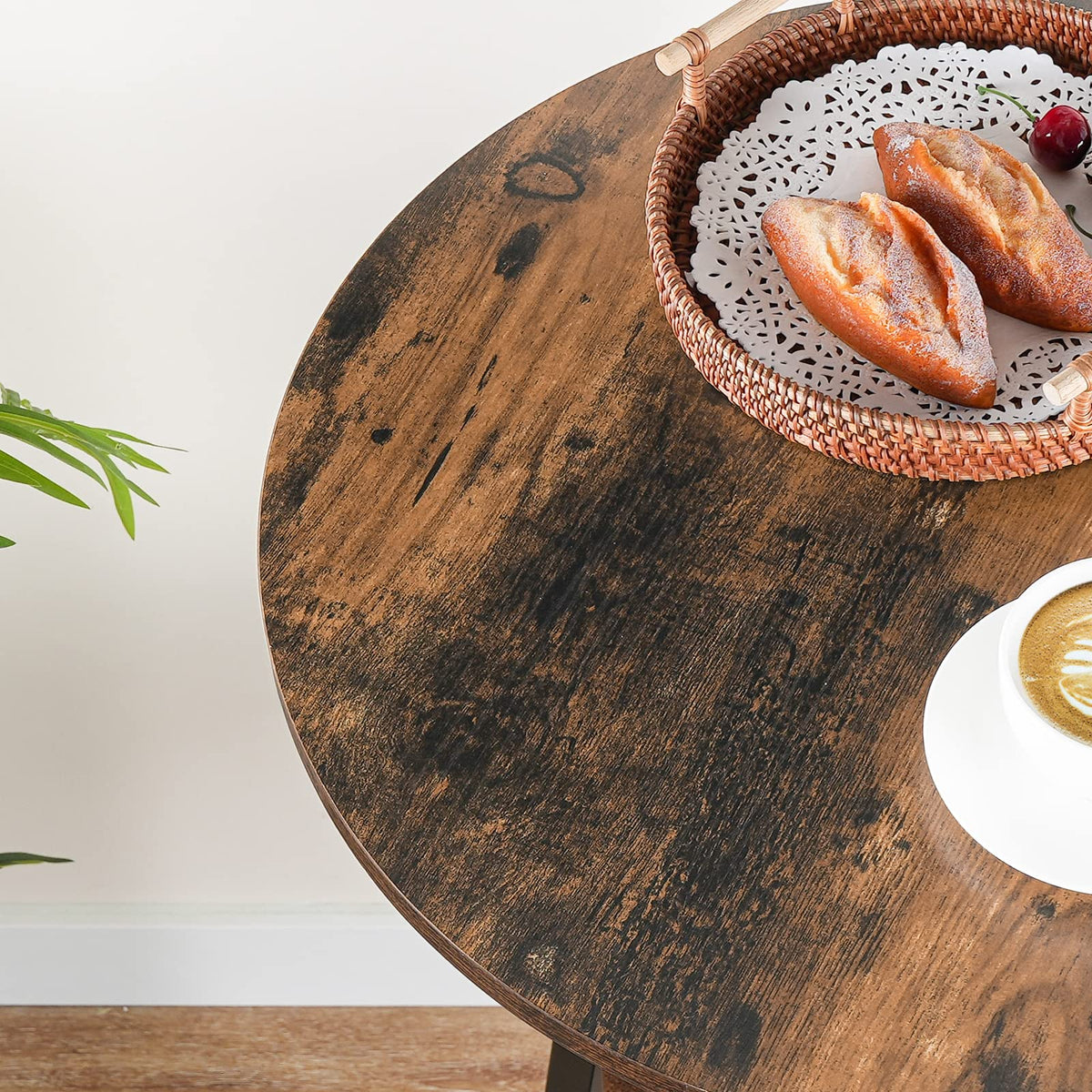 Close up of the rustic brown round tabletop with vintage wood grain finish holding a woven basket of bread.
